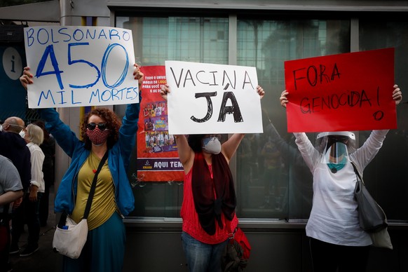 epa09236298 People hold placards reading (L-R) &#039;Bolsonaro 450,000 dead&#039;, &#039;Vaccine now&#039; and &#039;#Out, Genocidal&#039; during a protest against Brazilian President Jair Bolsonaro a ...
