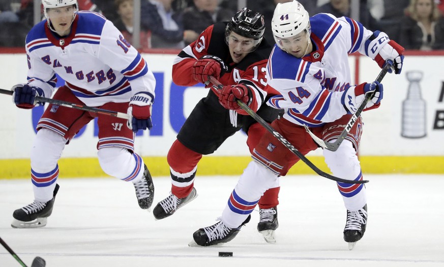New Jersey Devils center Nico Hischier (13), of Switzerland, competes for the puck with New York Rangers defenseman Neal Pionk (44) during the third period of an NHL hockey game, Monday, April 1, 2019 ...