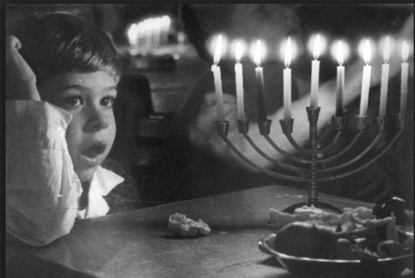 Am Ende der Festzeit brennen alle Kerzen: Ein Kind mit Chanukka-Leuchter.