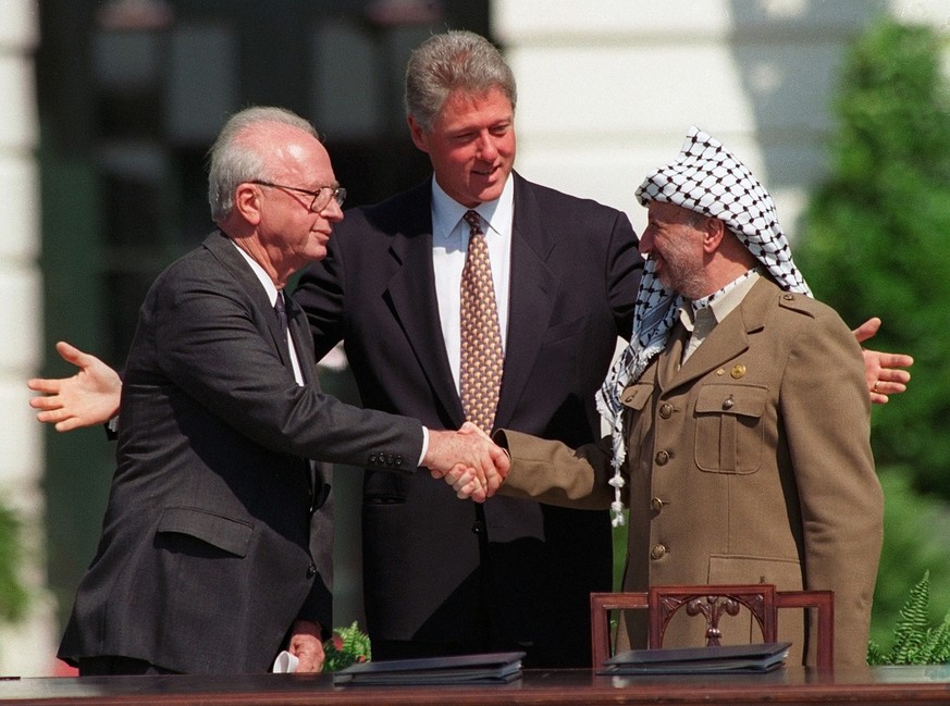 PLO leader Yasser Arafat, right, shakes hands with Israeli Prime Minister Yitzhak Rabin, left, under the glance of US President Bill Clinton, center, in Washington D.C. USA, September 13, 1993, after  ...