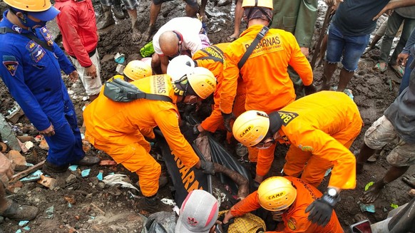epa09116536 A handout photo made available by the Indonesian National Search and Rescue Agency (BASARNAS) shows rescuers recovering the body of a flash flood victim during a search and rescue operatio ...