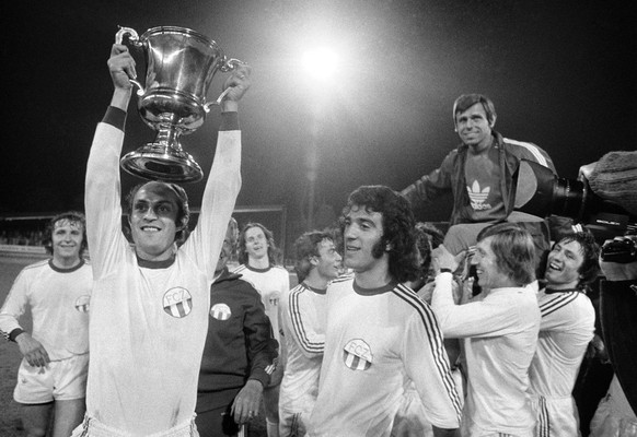 Die Spieler des FC Zuerich werden am 11. Mai 1974 in Zuerich als Schweizermeister gefeiert. V.l.n.r, jubeln die FCZ-Spieler Ernst Rutschmann, Renzo Bionda mit Pokal, Rene Botteron im Hintergrund und T ...
