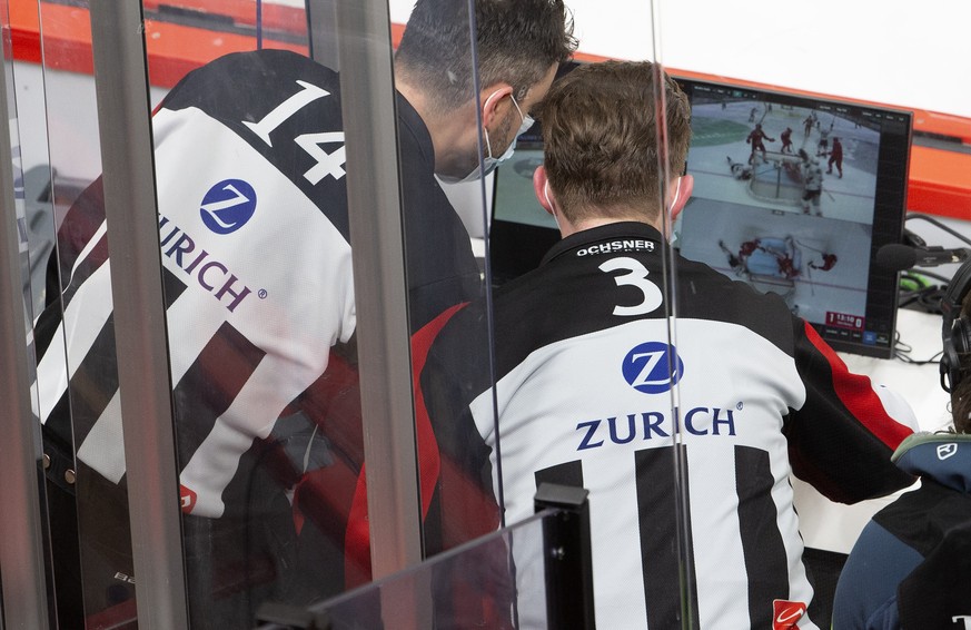 Head referee Mark Lemelin, and Head referee Manuel Nikolic, right, consults the video to check whether to award the goal, during a National League regular season game of the Swiss Championship between ...