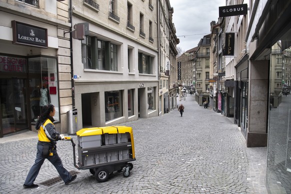 A postman is walking down a shopping street (Rue de Bourg) as stores are closed during the Covid-19 Coronavirus pandemic in Lausanne, Switzerland, Monday, March 23, 2020. The Swiss authorities proclai ...