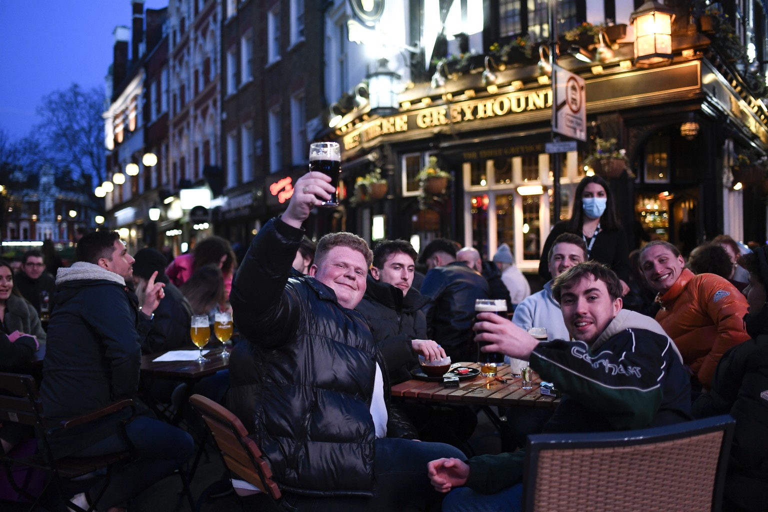 People sit at setup tables outside a pub in Soho, in London, on the day some of England&#039;s third coronavirus lockdown restrictions were eased by the British government, Monday, April 12, 2021. Pub ...