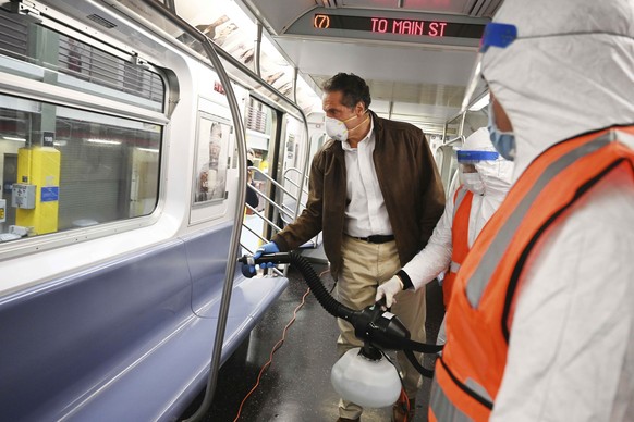 In this photo provided by the Office of Governor Andrew M. Cuomo, New York Gov. Cuomo tries out a spraying device which is part of a three-step disinfecting process of a New York City subway car at th ...