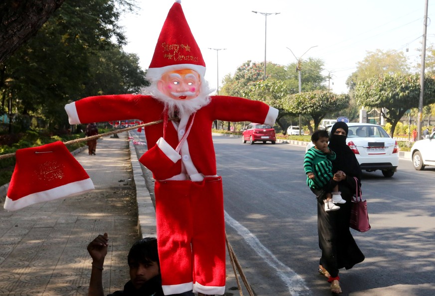 epa07239953 Santa Claus caps, masks and dresses on display at a roadside for sale ahead of the Christmas in Bhopal, India, 19 December 2018. Christmas is celebrated in India and across the world on 25 ...