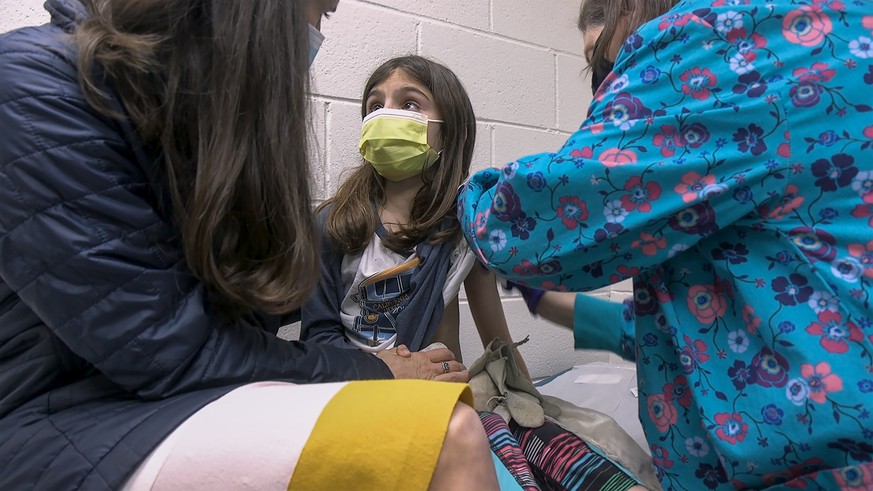 In this Wednesday, March 24, 2021 image from video provided by Duke Health, Alejandra Gerardo, 9, looks up to her mom, Dr. Susanna Naggie, as she gets the first of two Pfizer COVID-19 vaccinations dur ...