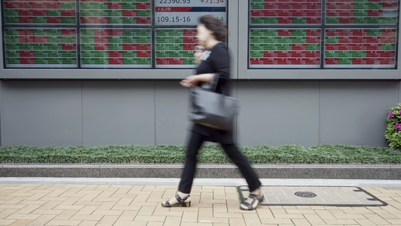 A woman walks past an electronic stock board showing Japan&#039;s Nikkei 225 index at a securities firm in Tokyo Friday, April 27, 2018. Asian stock markets followed Wall Street higher on Friday after ...