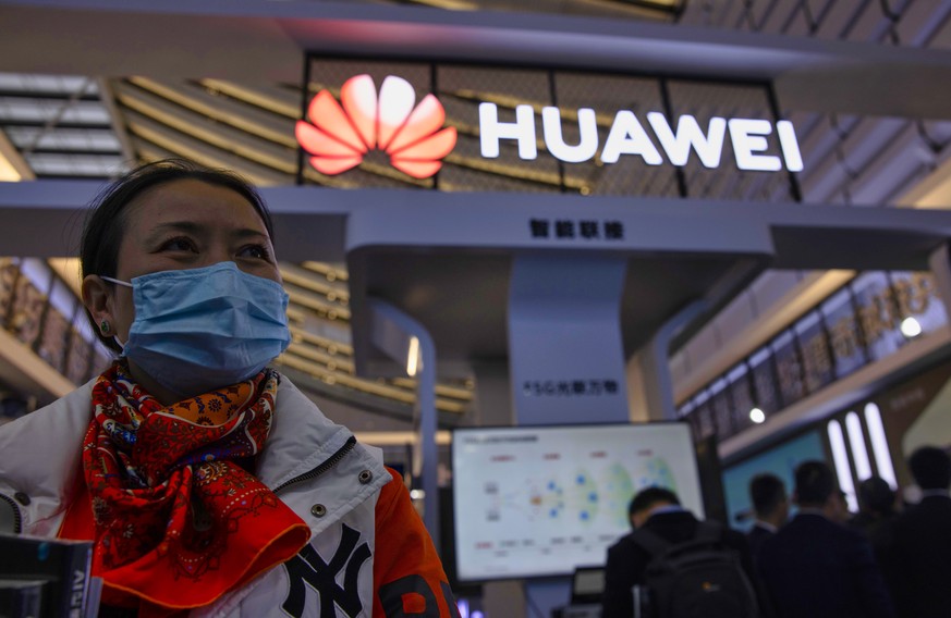 epa08837099 A woman stands in front of the Huawei booth on ?Light Of The Internet Expo? during World Internet Conference in Wuzhen, Zhejiang Province, China, 23 November 2020. The World Internet Confe ...