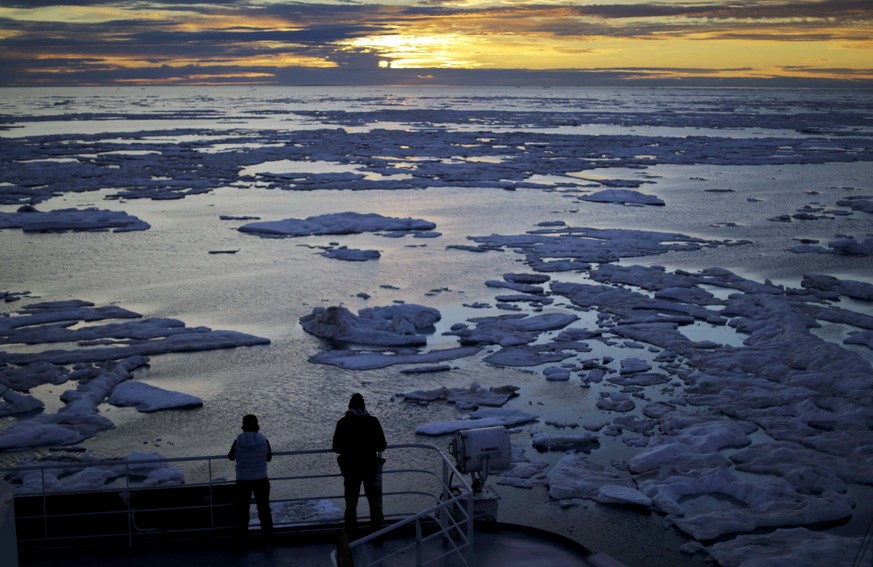 FILE - In this July 21, 2017 file photo, researchers look out from the Finnish icebreaker MSV Nordica as the sun sets over sea ice in the Victoria Strait along the Northwest Passage in the Canadian Ar ...