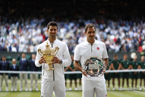 epa07717321 Novak Djokovic of Serbia (L) with the championship trophy after defeating Roger Federer of Switzerland (R) in the men&#039;s final of the Wimbledon Championships at the All England Lawn Te ...