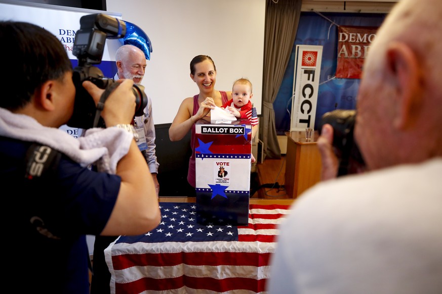 epa08266013 Democratic voter Sara Boyorak (C) holds her daughter Sally (C-R) as she casts her ballot for the US Democratic presidential nominee at a polling station for the Democrats Abroad Global Pre ...