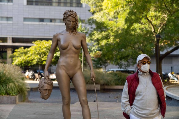October 14, 2020, New York City, United States: A man wearing a face mask poses for a photo next to the newly installed statue of Medusa With The Head of Perseus by Argentine-Italian artist Luciano Ga ...