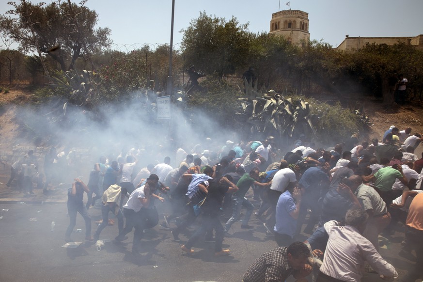 epa06101196 Palestinians scatter as Israeli Border Police push a crowd of several thousand Muslim worshippers back as stun grenades are thrown when clashes broke out following a mass Friday prayer on  ...