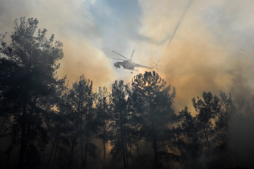 epa09388641 A firefighting helicopter sprays water during the second day of the wildfire in Rhodes island, Greece, 02 August 2021. The fronts of the fire on the island of Rhodes are in recession, as a ...