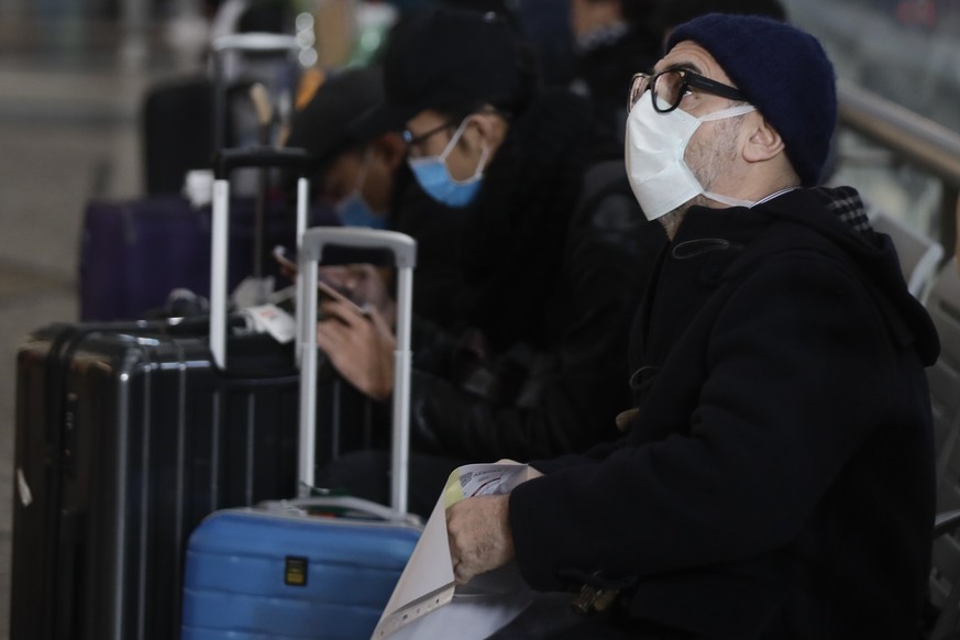 People wearing sanitary masks sit as they wait at the Centrale main railway station in Milan, Italy, Monday, Feb. 24, 2020. Italy has been scrambling to check the spread of Europe&#039;s first major o ...
