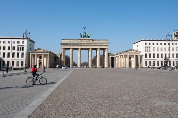 07.04.2020, Berlin: Ein Radfahrer steht vor dem Brandenburger Tor. An dem Touristen-Hotspot sind trotz des guten Wetters fast keine Besucher. Um die Ausbreitung des Coronavirus zu verlangsamen hat die ...
