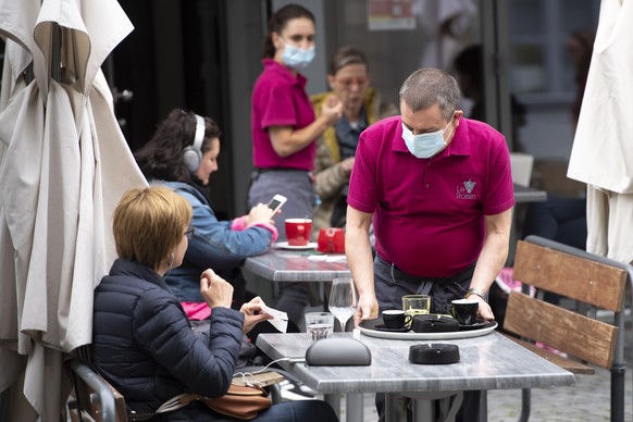A waiter wearing protective face mask of &quot;Le Raisin&quot; cafe restaurant brings drinks to customers in a terrace the day of its reopening during the state of emergency of the coronavirus disease ...