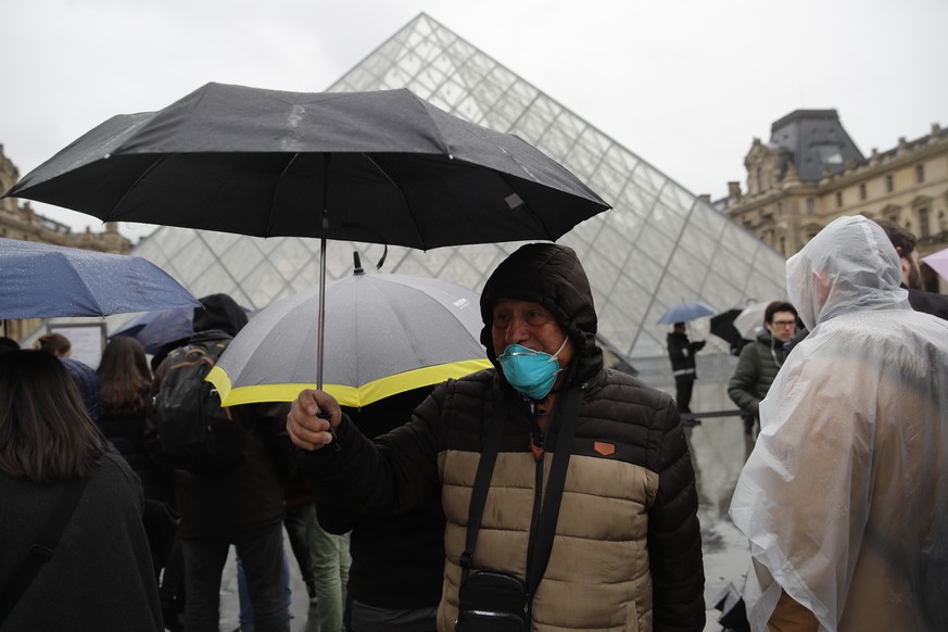 A tourist wearing a mask walks away from the Louvre museum in Paris, Monday, March 2, 2020. The Louvre Museum was closed again Monday as management was meeting with staff worried about the spread of t ...