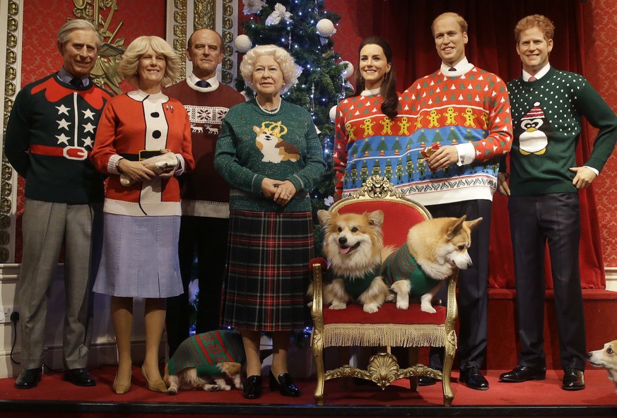 A dog owner tells her Pembrokeshire Welsh Corgi to &#039;stay&#039; as four Corgi dogs pose next to wax work models of the British Royal family wearing colorful Christmas themed jumpers for a charity  ...