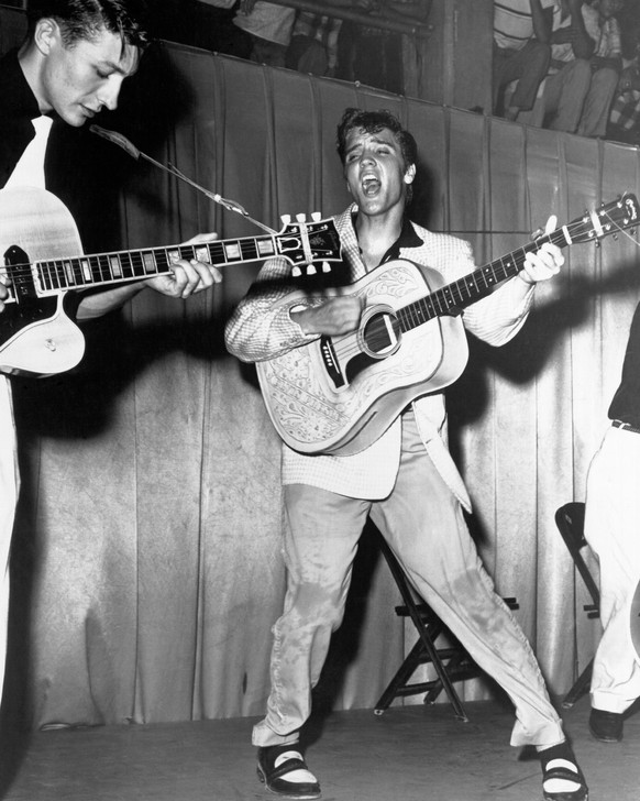 TAMPA, FL - JULY 31: Rock and roll singer Elvis Presley performs on stage with his brand new Martin D-28 acoustic guitar and Scotty Moore on the left on July 31, 1955 at Fort Homer Hesterly Armory in  ...