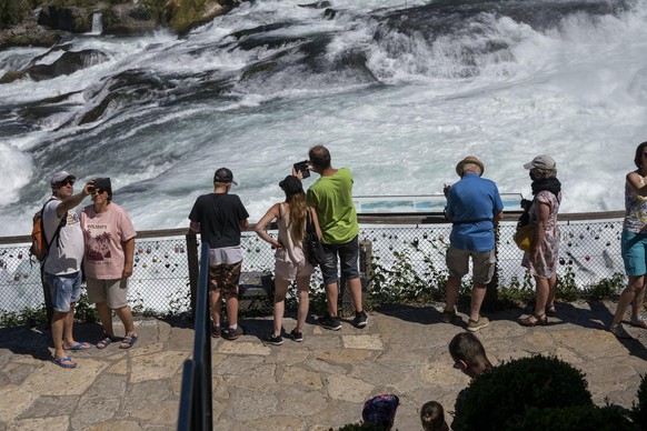 Besucher bestaunen und fotografieren die Wassermassen des Rheinfalls am Montag, 27. Juli 2020, in Neuhausen. (KEYSTONE/Christian Beutler)