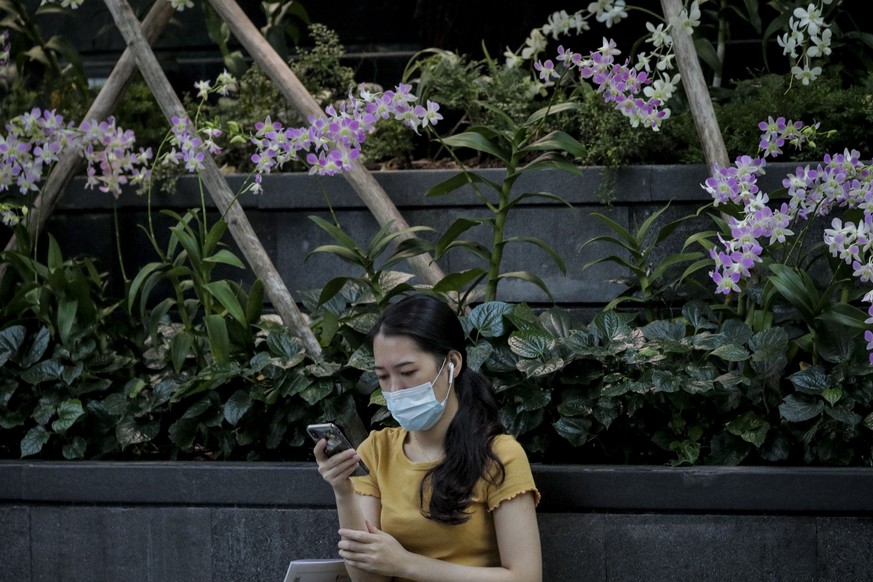 epa08315137 A woman wearing a surgical mask uses her phone at the Jewel Changi Airport mall in Singapore, 23 March 2020. Singapore Airlines has announced that they will be cutting 96 percent of their  ...