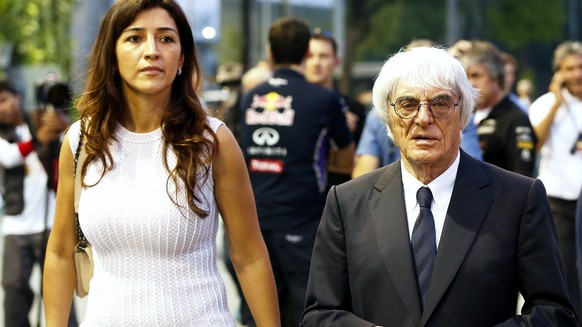 epa05450706 (FILE) A file picture dated 18 September 2014 shows Formula One (F1) boss Bernie Ecclestone (R) and his wife Fabiana Flosi (L) walking through the paddock at the Marina Bay Formula One str ...
