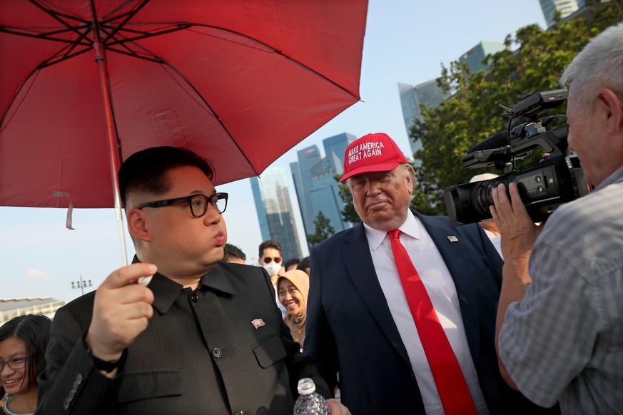 epa06792914 A television cameraman films North Korean leader Kim Jong-un impersonator Howard (L) and US President Donald Trump impersonator Dennis (C-R) as they pose for photographers in Singapore, 08 ...