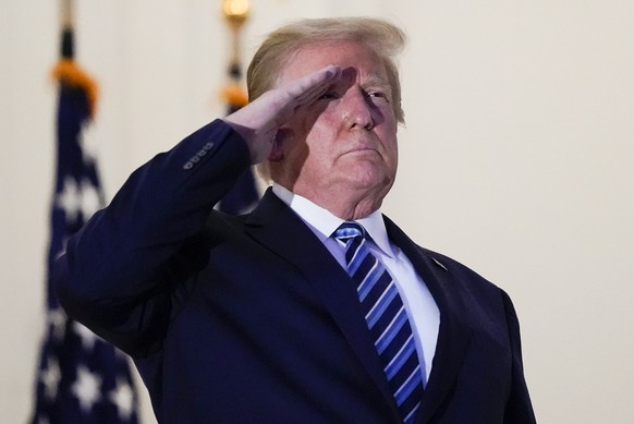 President Donald Trump salutes to Marine One as he stands on the balcony outside of the Blue Room as returns to the White House Monday, Oct. 5, 2020, in Washington, after leaving Walter Reed National  ...