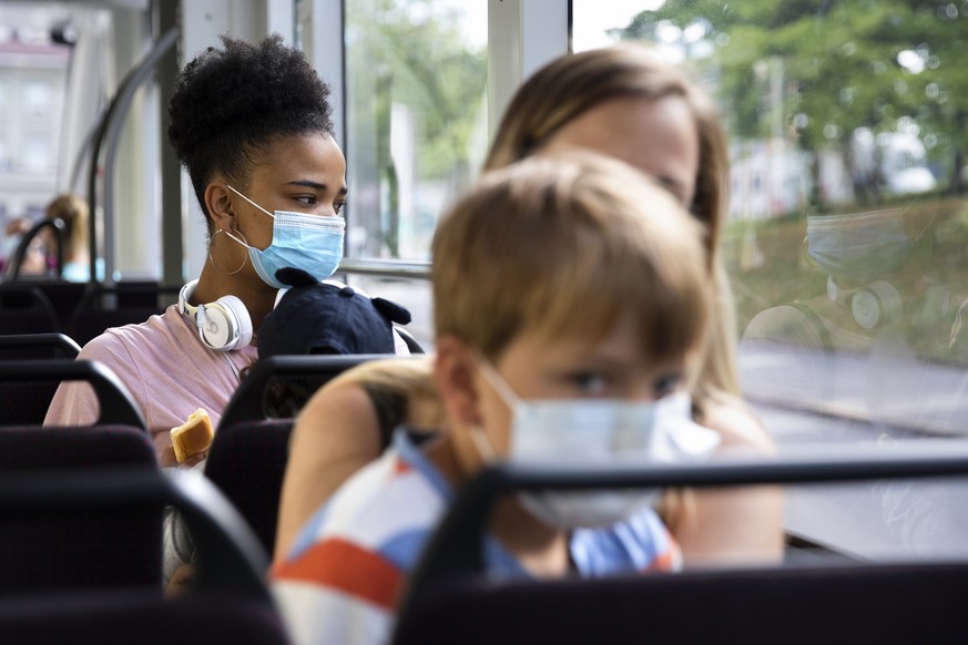Women and children wearing protective masks sit in a tram in Bern, Switzerland, Monday, July 6, 2020. Swiss authorities have mandated the use of face masks, starting on 06 July, for all people aged 12 ...