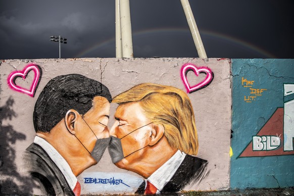 epaselect epa08392224 A view of a rainbow over a mural of US President Donald Trump (R) and Chinese President Xi Jinping kissing while surgical face masks at Mauerpark (Wall Park) in Berlin, Germany,  ...