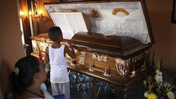 FILE - In this Aug. 23, 2017 file photo, a boy looks into the coffin holding the body of Candido Rios Vazquez, a journalist for the Diario de Acayucan newspaper who was murdered in Covarrubias, Hueyap ...