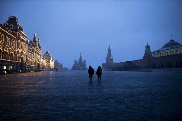 Two police officers patrol an almost empty Red Square, with St. Basil&#039;s Cathedral, center, and Spasskaya Tower and the Kremlin Wall, right, at the time when its usually very crowded in Moscow, Ru ...