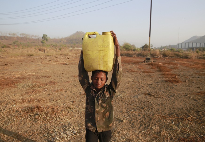 In this April 12, 2016 photo, a boy who migrated from drought hit areas of the western Indian state of Maharashtra, carries water to his family&#039;s makeshift hut in Kukse Borivali, 85 kilometres (5 ...