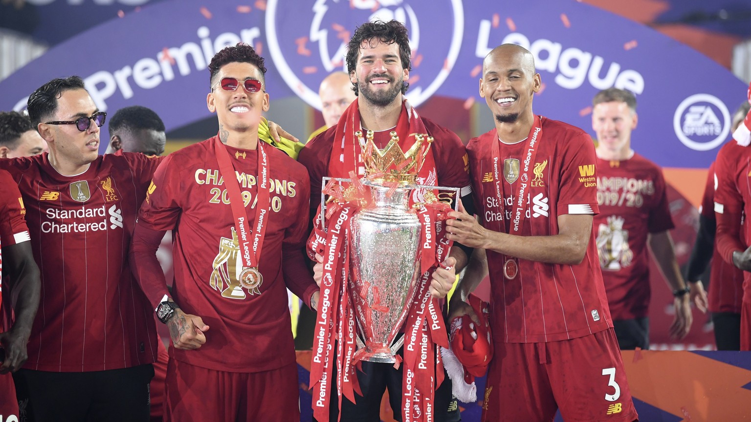 Liverpool&#039;s Fabinho, right, Liverpool&#039;s goalkeeper Alisson, center, and Roberto Firmino, all from Brazil, celebrate with the English Premier League trophy following the English Premier Leagu ...