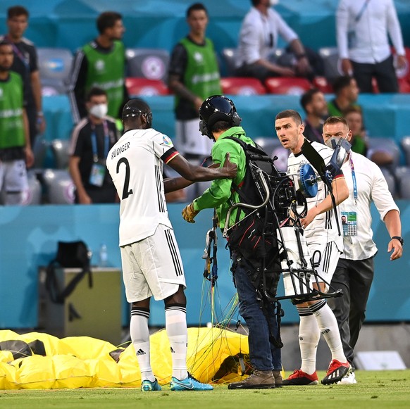 epa09274409 German players ask a Greenpeace activist (C), who landed with a parachute, to leave the pitch prior to the UEFA EURO 2020 group F preliminary round soccer match between France and Germany  ...