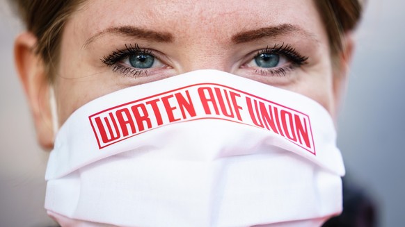 epa08428336 A steward wears a face mask reading &quot;waiting for Union&quot; outside the Alte Foersterei stadium prior to the Bundesliga soccer match between FC Union Berlin and FC Bayern Munich in B ...
