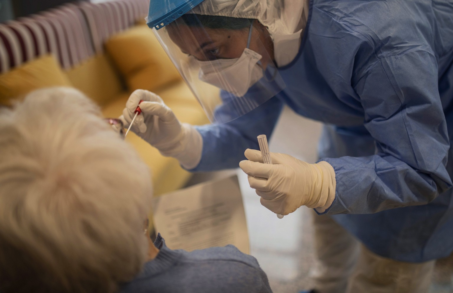 In this photo taken on Wednesday April 1, 2020, an aid worker from the Spanish NGO Open Arms carries out a coronavirus detection test on an elderly woman at a nursing home in Barcelona, Spain. The ini ...