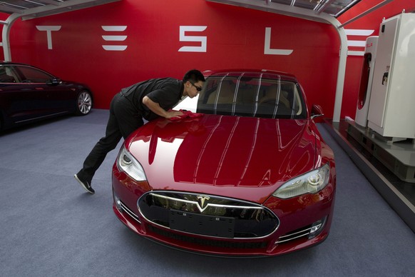 A worker cleans a Tesla Model S sedan before a event to deliver the first set of cars to customers in Beijing, China, Tuesday, April 22, 2014. Tesla Motors delivered its first eight electric sedans to ...