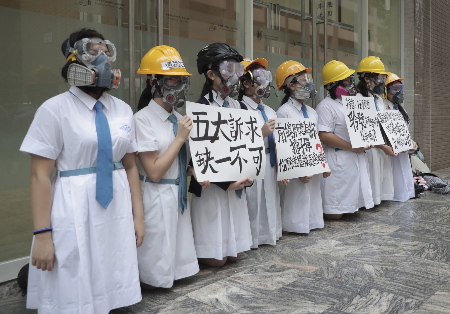 Students wearing gas masks and helmets hold a banner which reads &quot;Five major demands are indispensable.&quot;, at St. Francis&#039; Canossian College in Hong Kong, on Monday, Sept. 2, 2019. Hong  ...