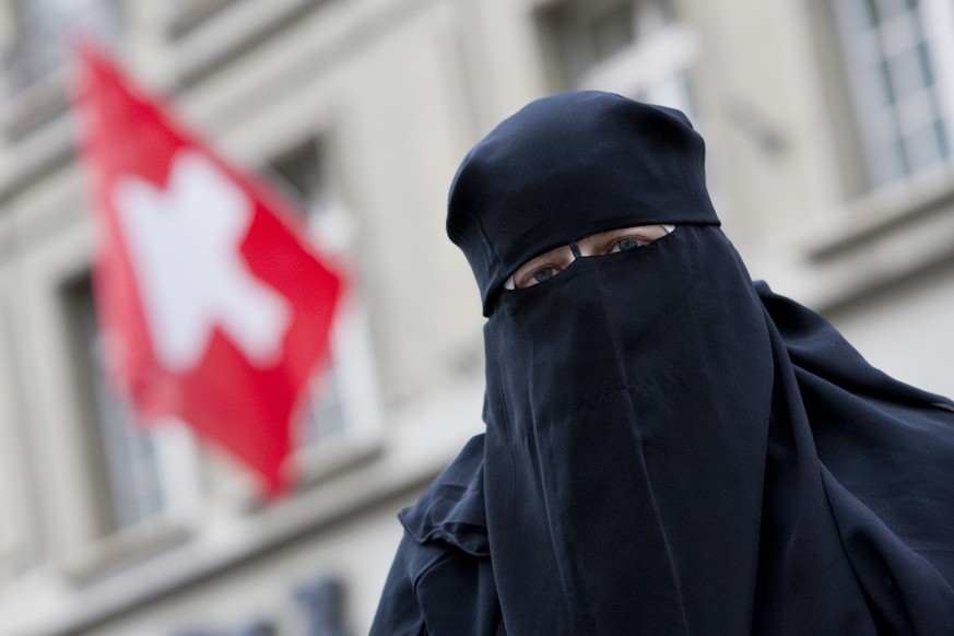 Warum sie zur Osterzeit Eier essen soll, ist ihr schleierhaft: grauenhaft plakativ fotografierte Muslima vor einer Schweizer Flagge.