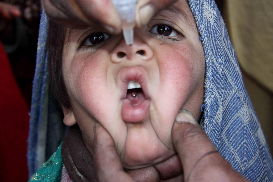 epa02558543 A Pakistani health worker gives a Polio vaccination to a child in Pakistan at Chaman border with Afghanistan, on 31 January 2011. Millions of children below five years of age are given pol ...