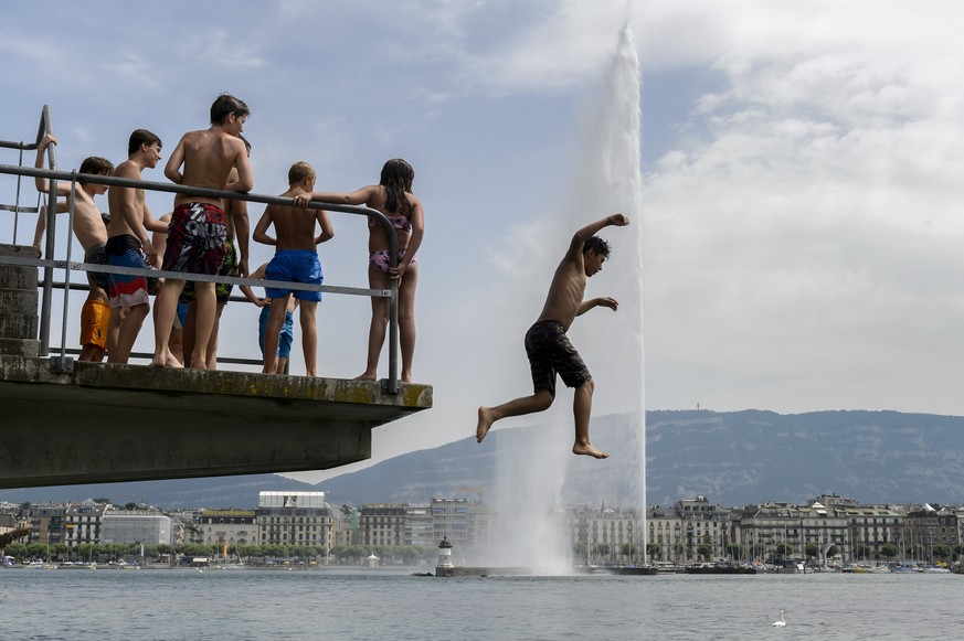 Une personne saute d&#039;un plongeoir face au jet d&#039;eau, ce vendredi 3 juillet 2015 aux Bains des Paquis a Geneve. Une masse d&#039;air chaud venue de l&#039;Atlas marocain a fait remonter de ma ...