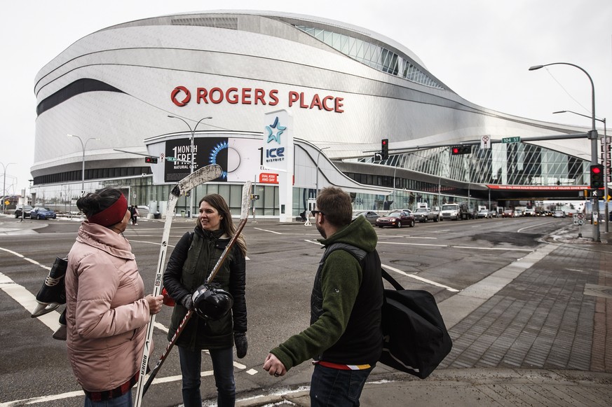People wait cross outside Rogers Place, the home ice of the NHL hockey club Edmonton Oilers, in Edmonton, Alberta, Thursday March 12, 2020. The NHL is following the NBAÄôs lead and suspending its sea ...