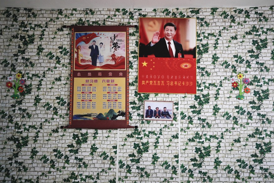Posters of Chinese President Xi Jinping and his wife Peng Liyuan are displayed on a wall with a photo of members of the Yi minority group inside their home in Xujiashan village in Ganluo County, south ...