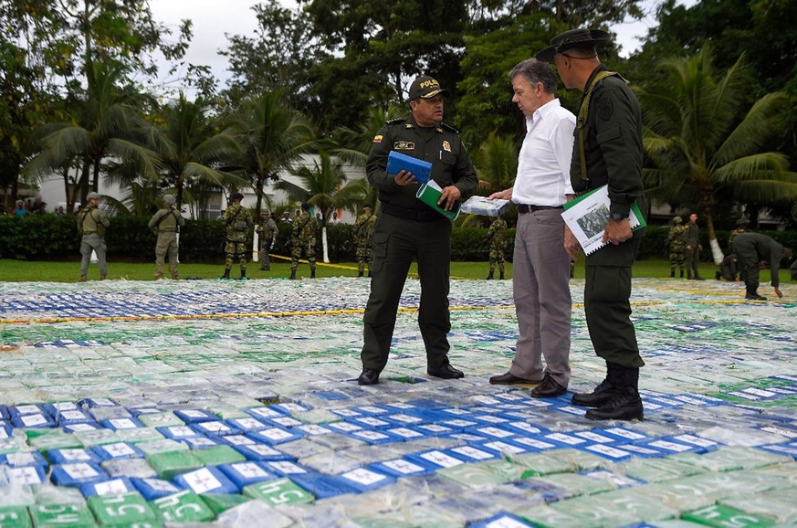 epa06316705 A handout photo made available by the Presidency of Colombiashows the Colombian President Juan Manuel Santos (C) speaking with police in the middle of packages containing cocaine, in Apart ...