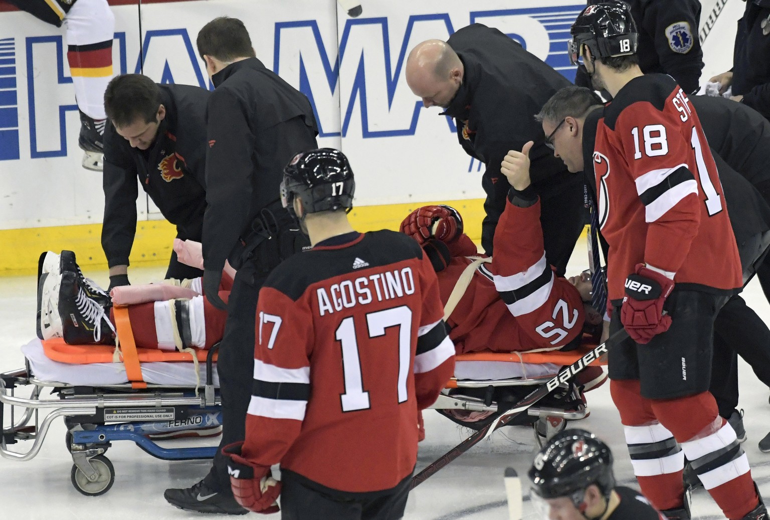 New Jersey Devils defenseman Mirco Mueller gives a thumbs-up sign as he is wheeled off the ice on a stretcher after being injured during the third period of an NHL hockey game against the Calgary Flam ...
