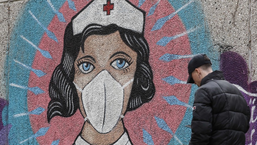 A man passes a graffiti by street artist &#039;Uzey&#039;, depicting a nurse as superhero in the coronavirus pandemic on a wall in Hamm, Germany, Monday, Sept. 28, 2020. The city of Hamm is the number ...
